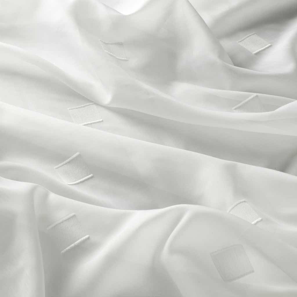 AUDREY Dieser zarte Scherli setzt auf kleine Quadrate als grafisches Motiv. Die feine Gardine präsentiert sich dabei in zwei Weiß-Nuancen und schafft somit einen frischen Look.